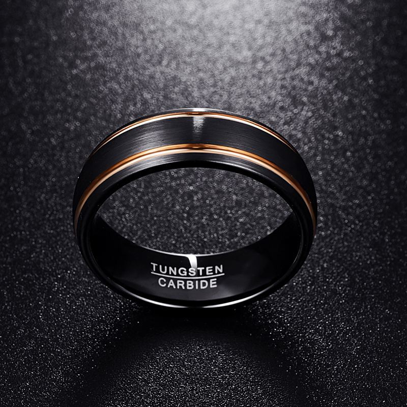 Black tungsten carbide ring with rose gold accents on a dark textured background